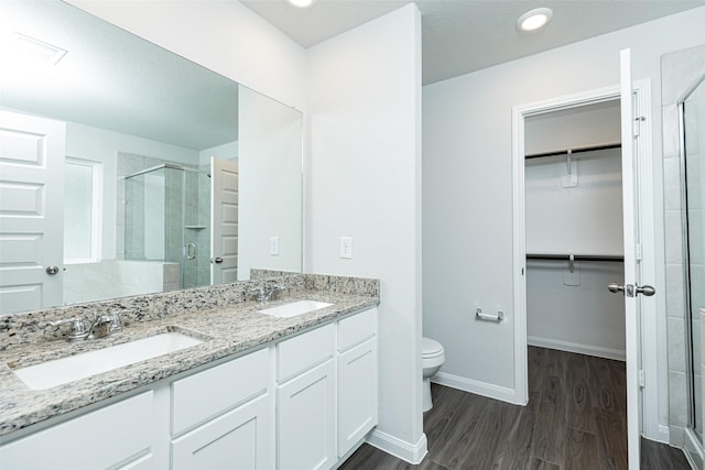 bathroom featuring wood-type flooring, toilet, vanity, and walk in shower