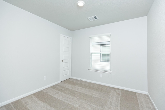 empty room with light carpet and a textured ceiling