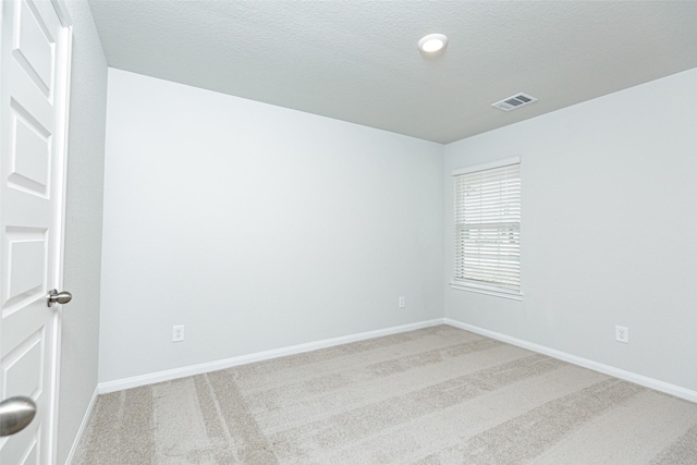 unfurnished room with light colored carpet and a textured ceiling