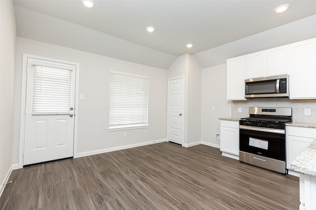 kitchen with dark wood-type flooring, appliances with stainless steel finishes, white cabinetry, tasteful backsplash, and vaulted ceiling