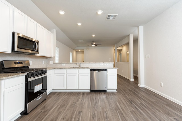 kitchen with sink, white cabinetry, stainless steel appliances, light stone countertops, and kitchen peninsula