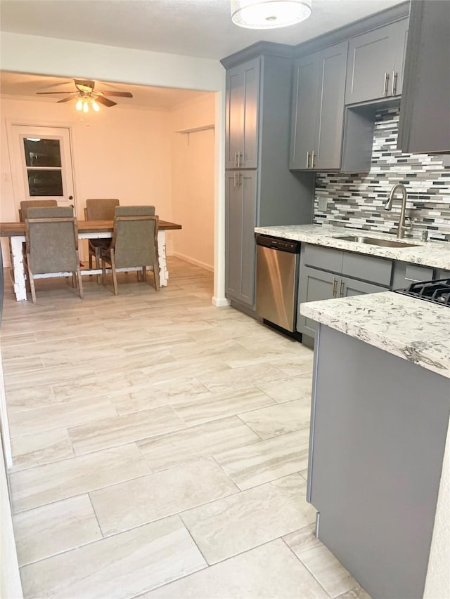 kitchen featuring sink, dishwasher, gray cabinetry, tasteful backsplash, and light stone counters