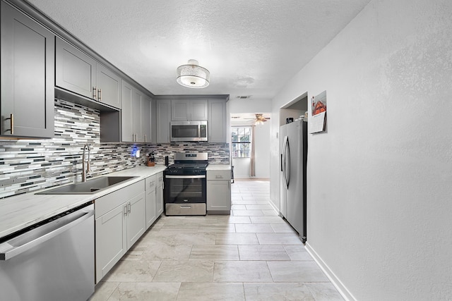 kitchen featuring stainless steel appliances, sink, decorative backsplash, and gray cabinetry