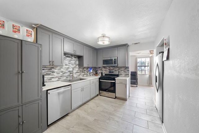 kitchen featuring stainless steel appliances, sink, and gray cabinetry