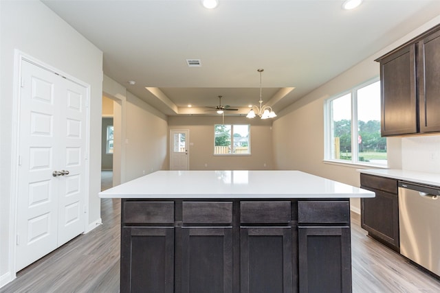 kitchen with dark brown cabinetry, stainless steel dishwasher, a raised ceiling, and a kitchen island