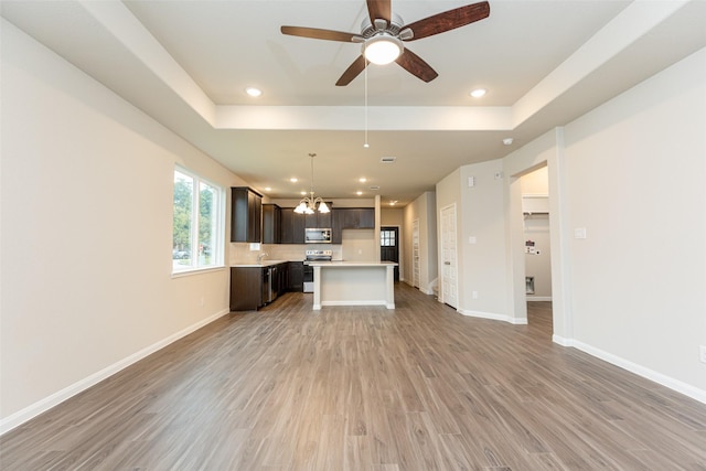 kitchen with hardwood / wood-style flooring, appliances with stainless steel finishes, a center island, and a tray ceiling