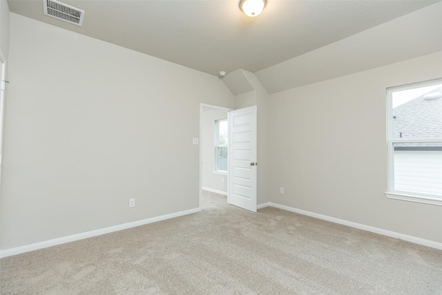 empty room featuring light colored carpet and lofted ceiling