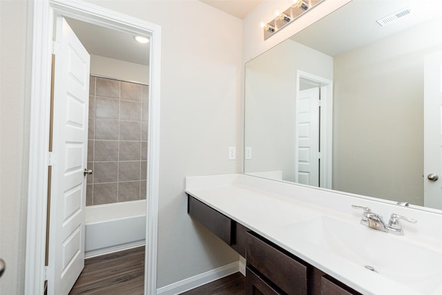 bathroom with vanity, tiled shower / bath combo, and wood-type flooring