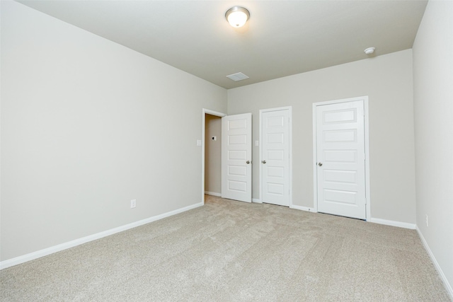 unfurnished bedroom with light carpet and multiple closets