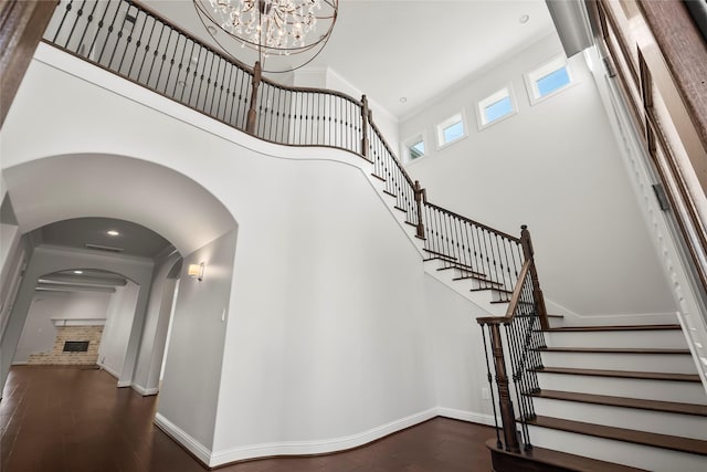 stairway featuring ornamental molding, wood-type flooring, a brick fireplace, and a high ceiling