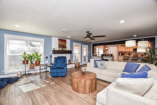 living room featuring ceiling fan, a fireplace, and wood-type flooring