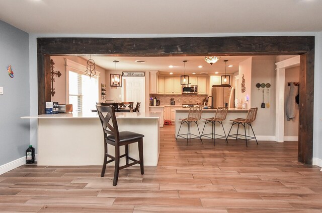 kitchen featuring a breakfast bar, pendant lighting, backsplash, kitchen peninsula, and stainless steel appliances