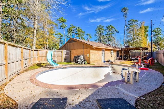 view of swimming pool with a water slide and a patio