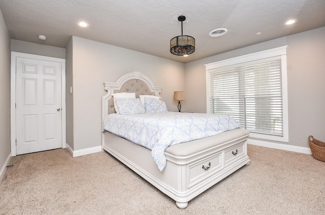 bedroom with light colored carpet and a textured ceiling