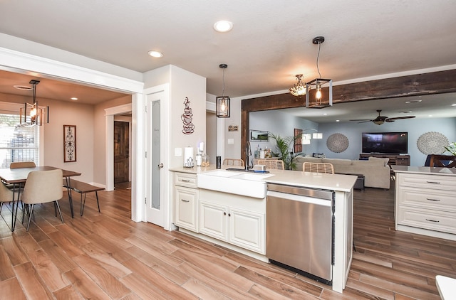 kitchen featuring hanging light fixtures, stainless steel dishwasher, sink, and white cabinets