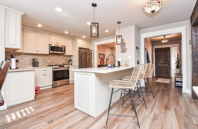 kitchen with white cabinetry, a kitchen bar, kitchen peninsula, and appliances with stainless steel finishes