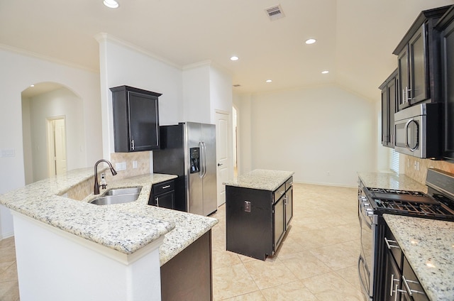 kitchen featuring appliances with stainless steel finishes, sink, decorative backsplash, a center island, and light stone counters