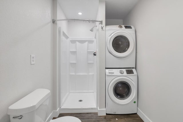 laundry area with stacked washer / dryer and dark hardwood / wood-style flooring