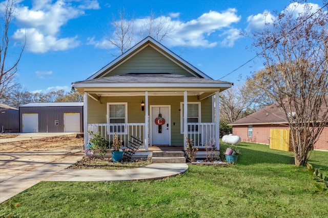 view of front facade with an outbuilding, a garage, a front yard, and a porch