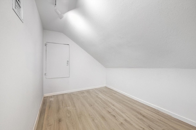 bonus room with vaulted ceiling, a textured ceiling, and light hardwood / wood-style floors