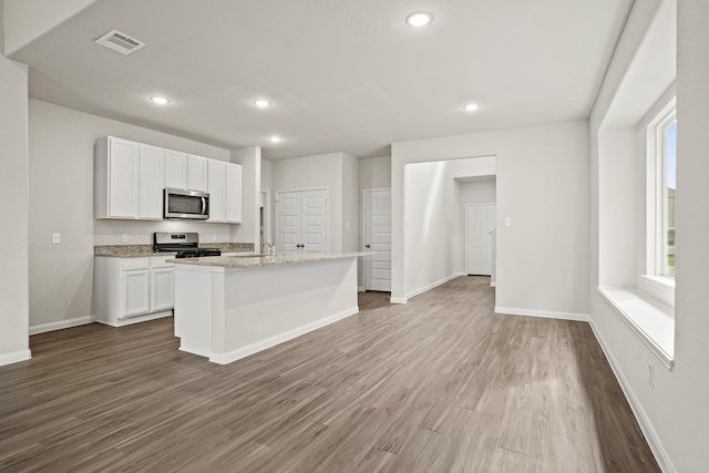 kitchen featuring dark wood finished floors, white cabinets, visible vents, stainless steel appliances, and baseboards
