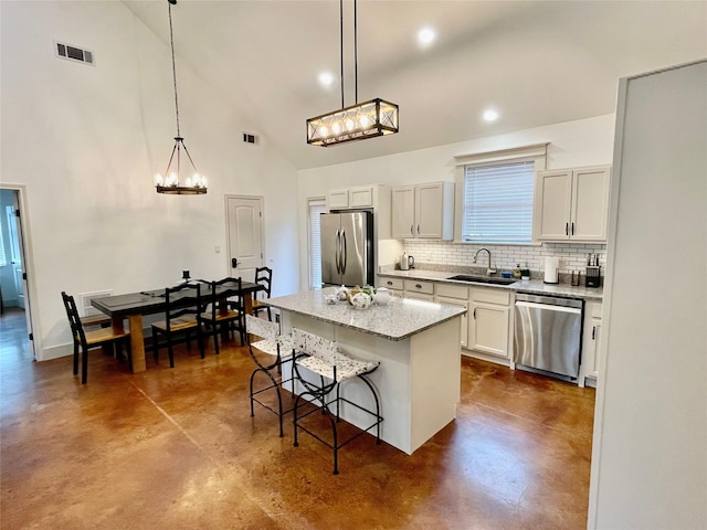 kitchen with a kitchen bar, tasteful backsplash, hanging light fixtures, a kitchen island, and stainless steel appliances