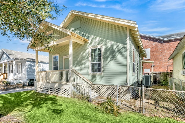 back of house featuring a porch, cooling unit, a lawn, and fence