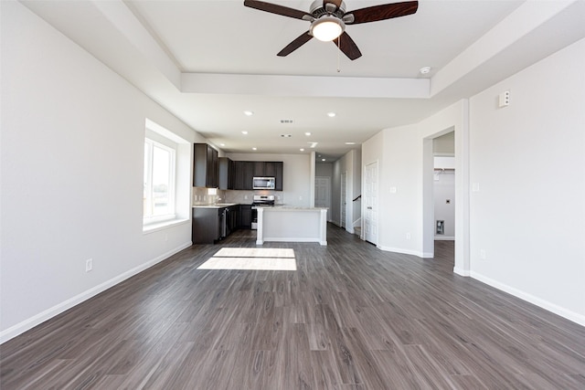 unfurnished living room with a tray ceiling, dark hardwood / wood-style floors, and ceiling fan