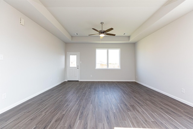 unfurnished room with dark hardwood / wood-style flooring, a raised ceiling, and ceiling fan