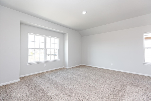 carpeted spare room featuring vaulted ceiling and a healthy amount of sunlight