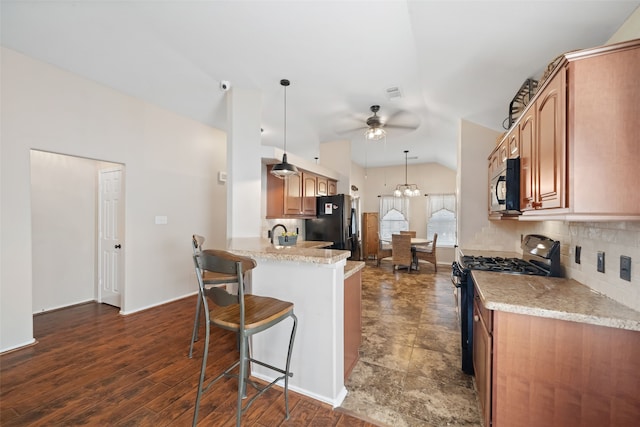 kitchen featuring lofted ceiling, range with gas cooktop, hanging light fixtures, kitchen peninsula, and backsplash