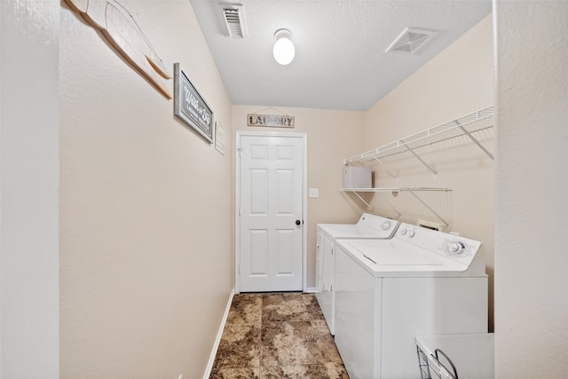 laundry area with washer and clothes dryer and a textured ceiling