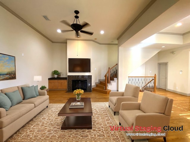 living area featuring crown molding, a premium fireplace, visible vents, and light wood-style floors