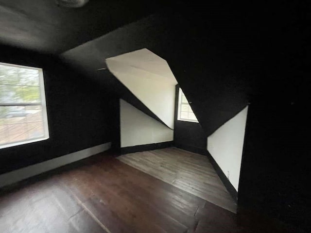 additional living space featuring dark wood-type flooring and lofted ceiling