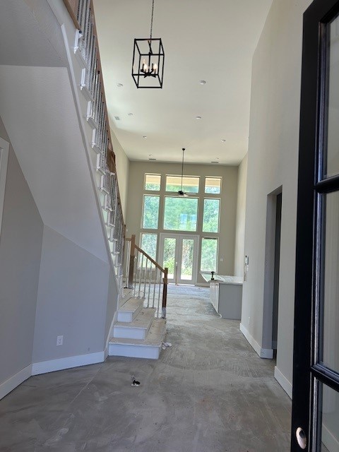 4423 Southpoint Way, Fulshear, TX 77441 - staircase featuring baseboards, a high ceiling, unfinished concrete flooring, and a chandelier