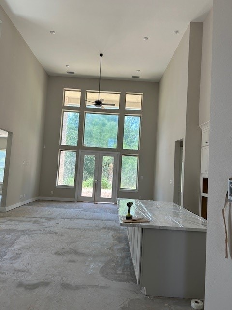 4423 Southpoint Way, Fulshear, TX 77441 - unfurnished living room with a towering ceiling, a ceiling fan, french doors, and baseboards