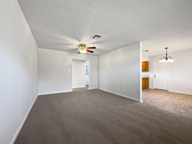 carpeted empty room featuring ceiling fan with notable chandelier and a textured ceiling