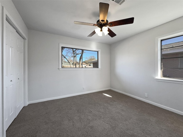 unfurnished bedroom featuring dark carpet, a closet, and ceiling fan