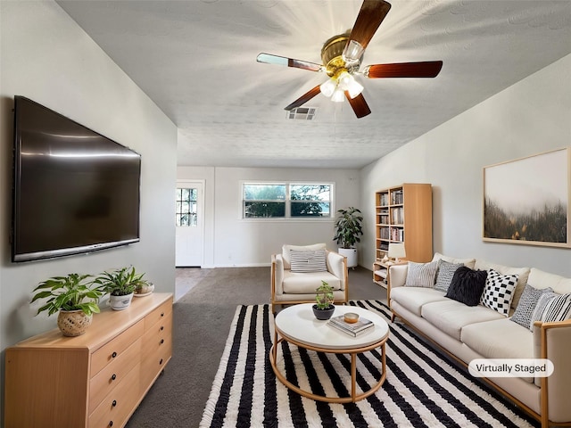 living room featuring ceiling fan, a textured ceiling, and dark colored carpet