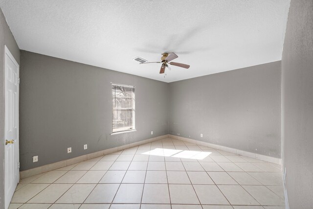 tiled empty room featuring ceiling fan and a textured ceiling