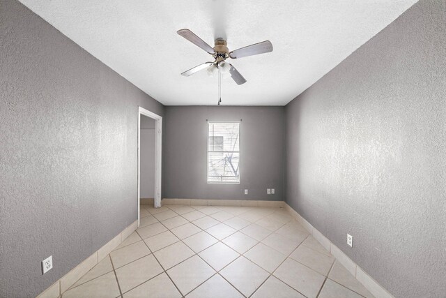 empty room featuring light tile patterned flooring, ceiling fan, and a textured ceiling