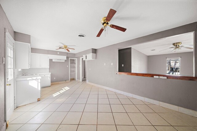 unfurnished living room featuring sink, light tile patterned floors, and ceiling fan