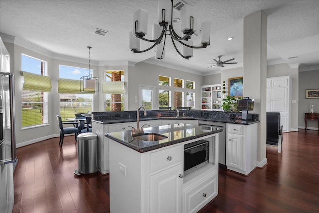 kitchen featuring white cabinetry, sink, a kitchen island with sink, kitchen peninsula, and a textured ceiling