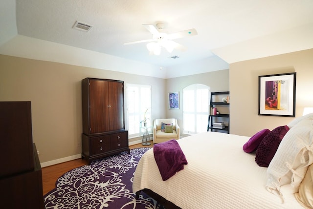 bedroom featuring ceiling fan, a raised ceiling, and light hardwood / wood-style floors