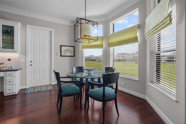 dining room featuring dark wood-type flooring, ornamental molding, and a textured ceiling