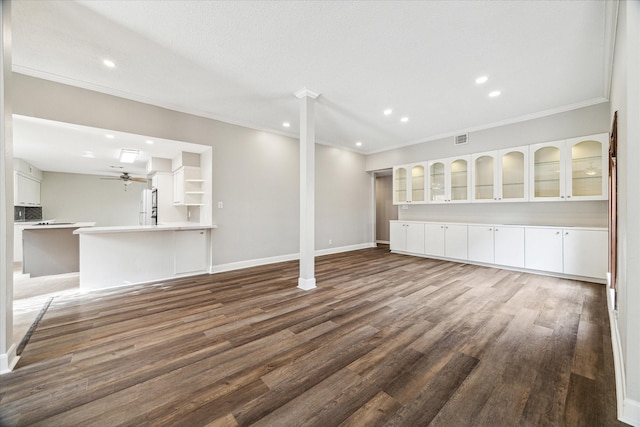 unfurnished living room with a textured ceiling, dark wood-type flooring, ornamental molding, and ceiling fan