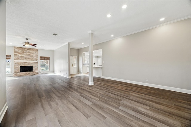 unfurnished living room with hardwood / wood-style floors, ornamental molding, a large fireplace, and ceiling fan