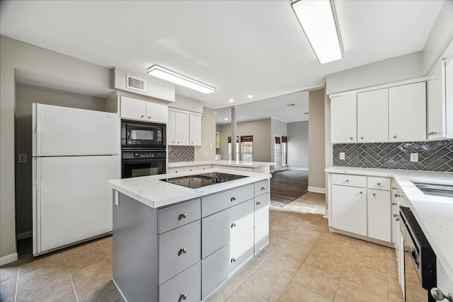 kitchen with backsplash, white cabinets, and black appliances