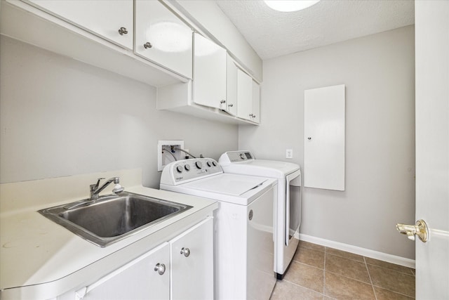 laundry room with sink, cabinets, washer and dryer, light tile patterned floors, and a textured ceiling