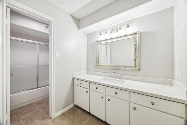 bathroom with enclosed tub / shower combo, vanity, and a textured ceiling